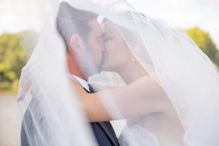 couple s'embrasse sous le voile de la mariée