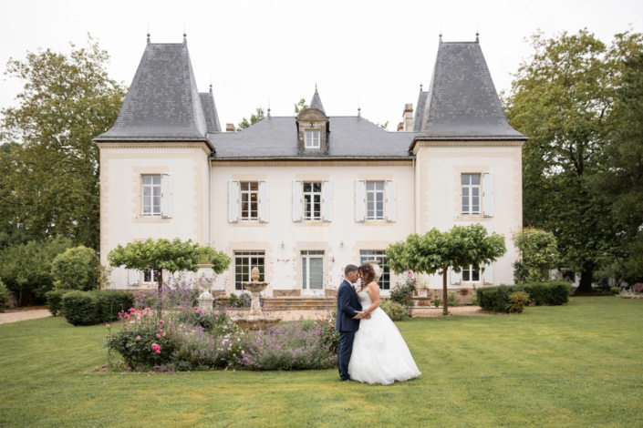 mariés posant devant le manoir de leur mariage